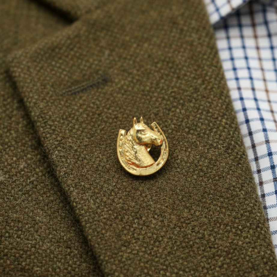 Gold horse-shaped lapel pin on a green jacket with a checkered shirt.